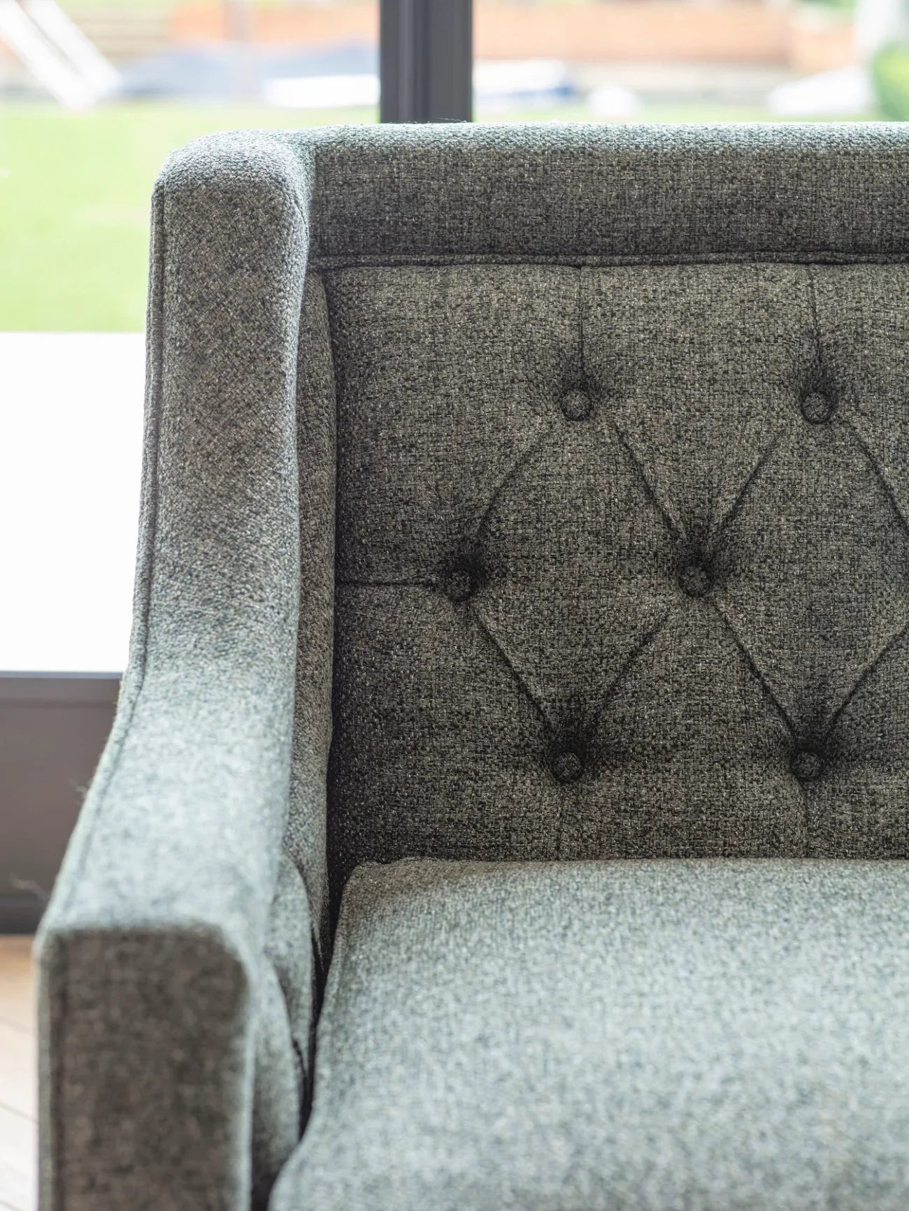 Forest green sofa with buttoned backrest and textured fabric.