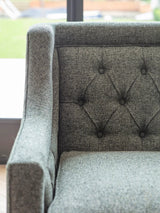 Forest green sofa with buttoned backrest and textured fabric.