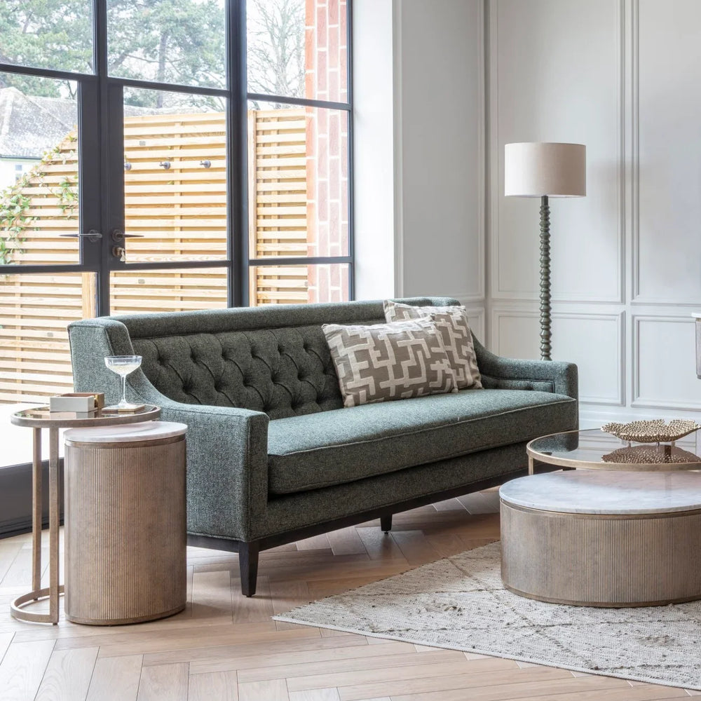 Forest green sofa in elegant living room with wooden tables and floor lamp.