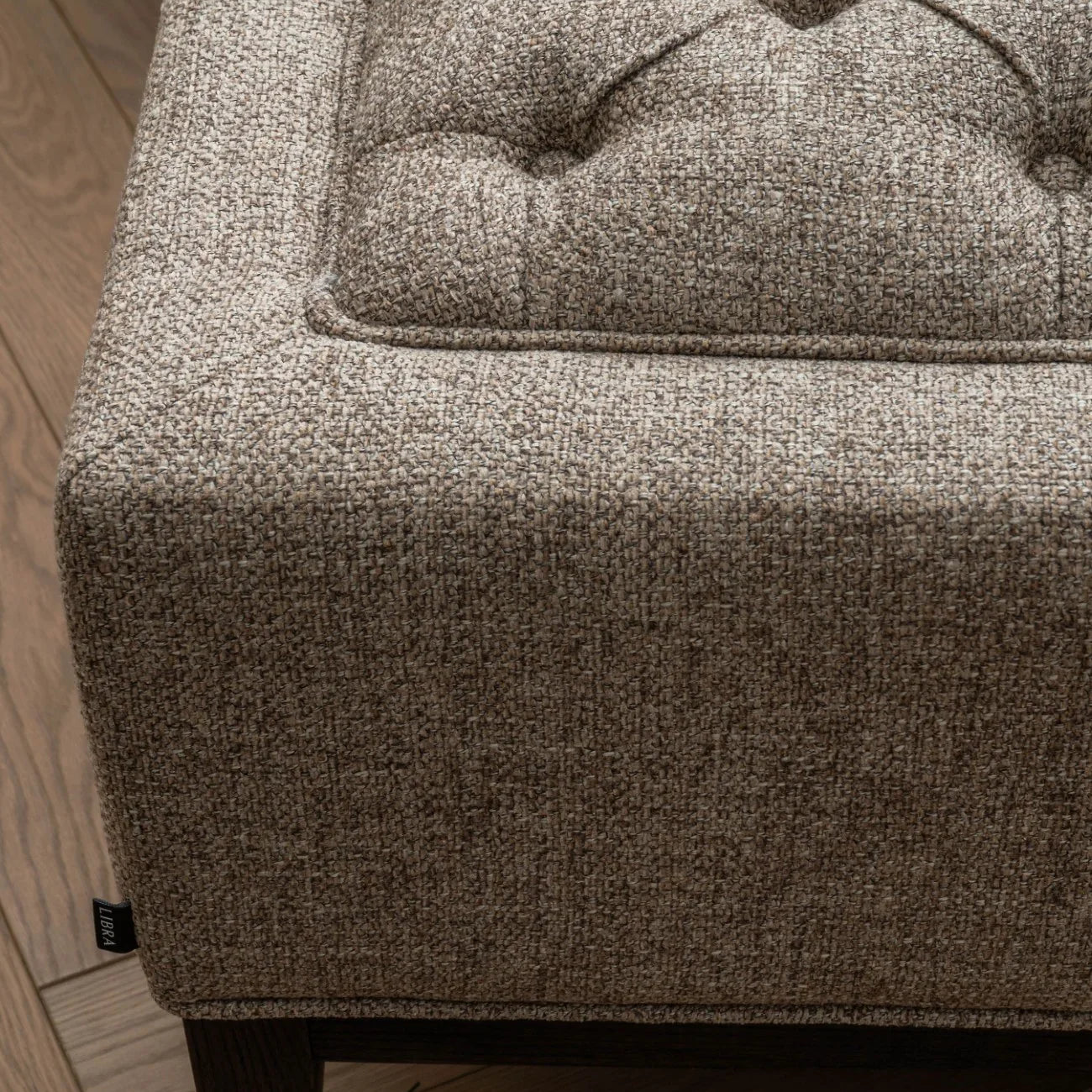 Dark taupe stool corner with buttoned texture and wooden leg detail.