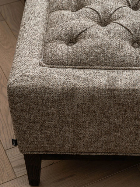 Dark taupe stool corner with buttoned texture and wooden leg detail.