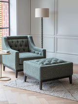 Forest green buttoned stool in elegant living room with matching armchair.