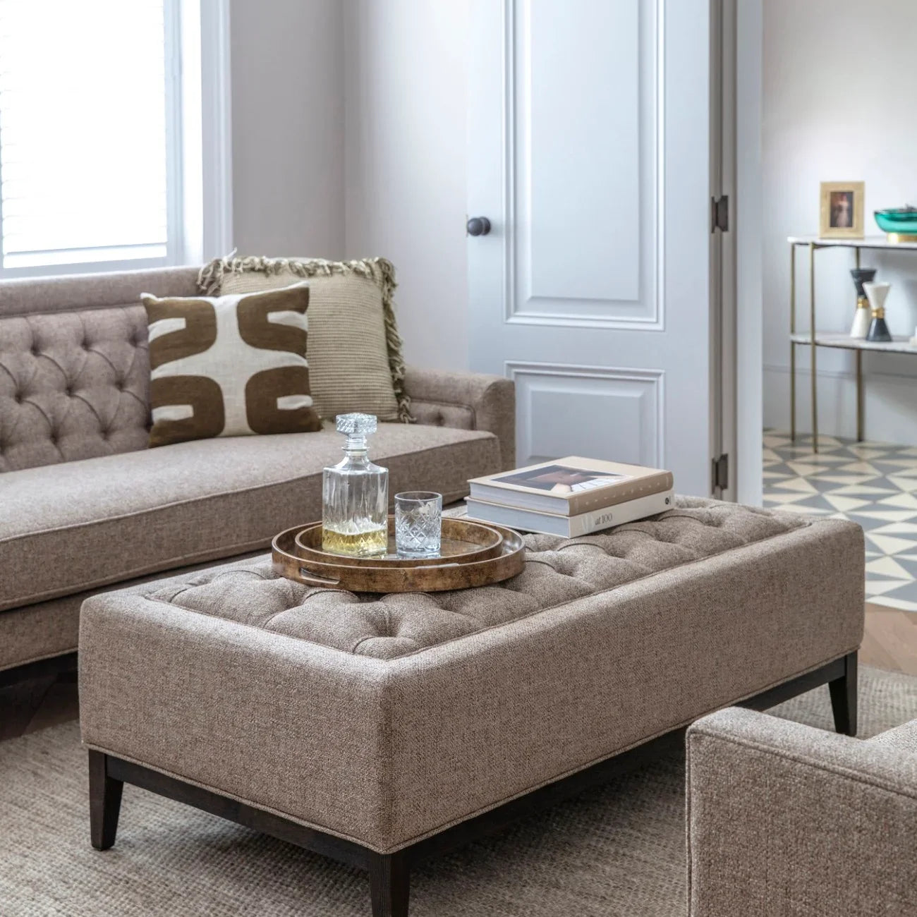 Dark taupe ottoman in a cozy living room with a tray and books on top.