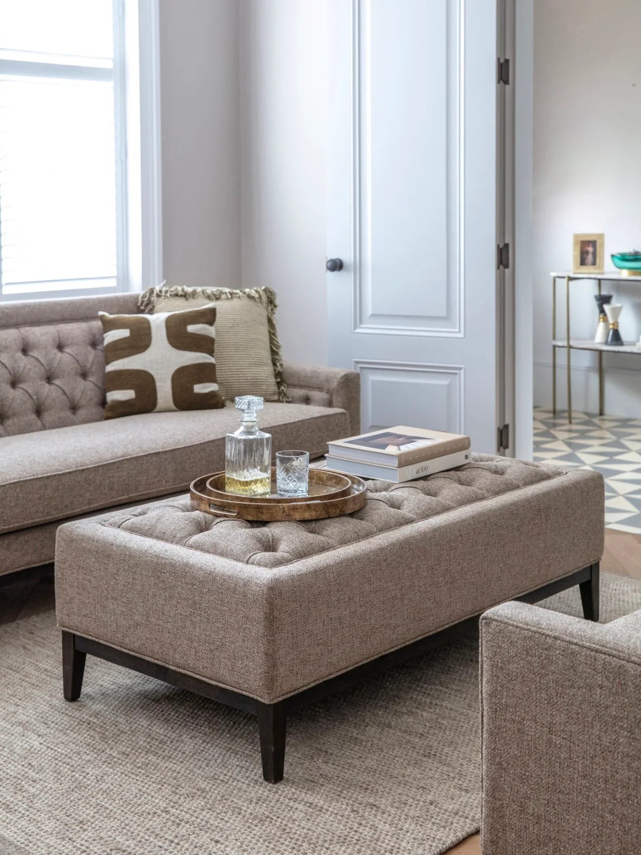 Dark taupe ottoman in a cozy living room with a tray and books on top.