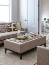 Dark taupe ottoman in a cozy living room with a tray and books on top.