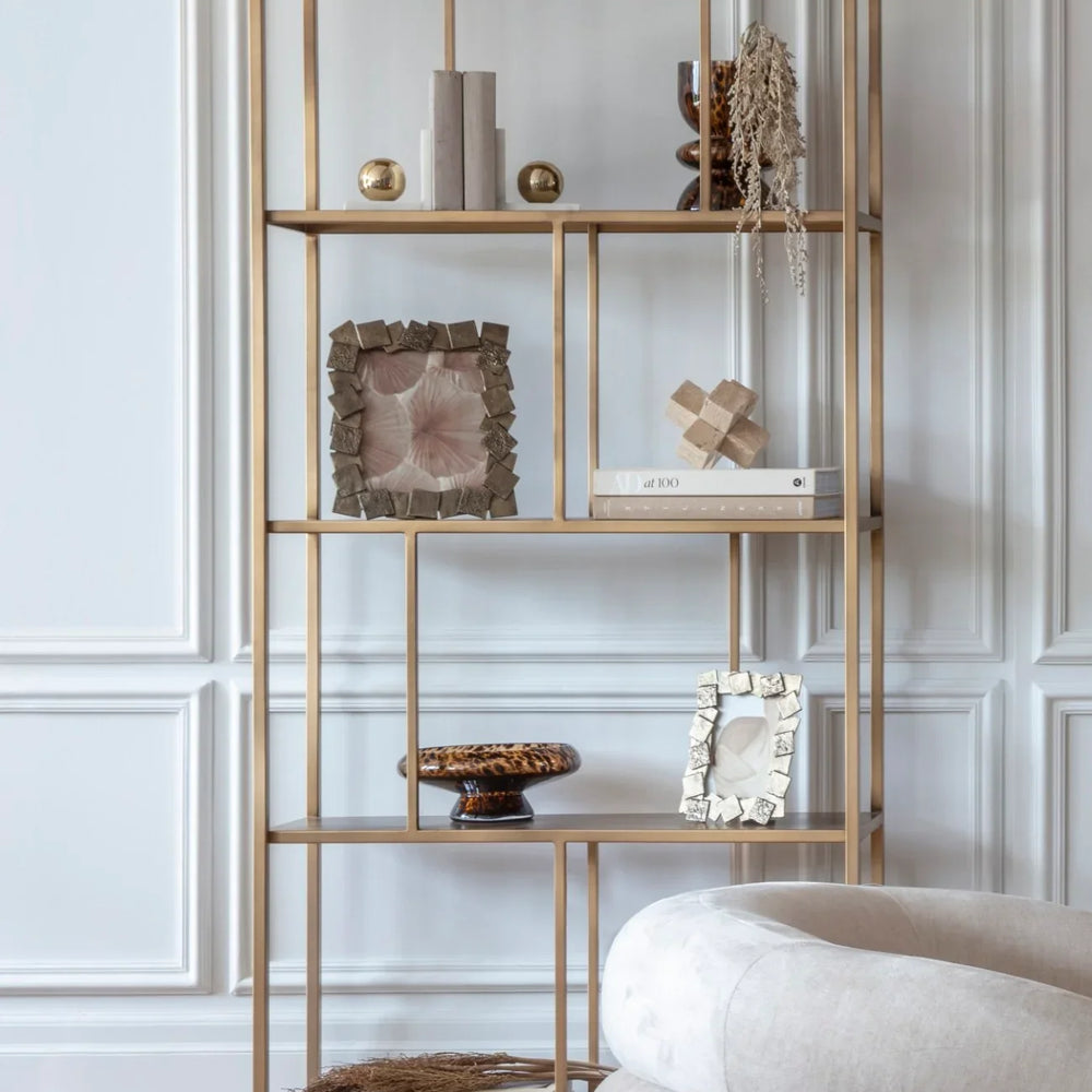 Brushed champagne shelving with decor in elegant living room setting.