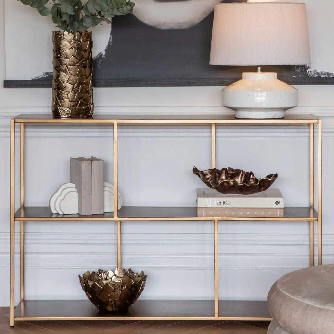 Brushed champagne console table with decorative items in elegant living room setting.