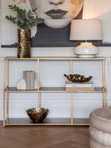 Brushed champagne console table with decorative items in elegant living room setting.
