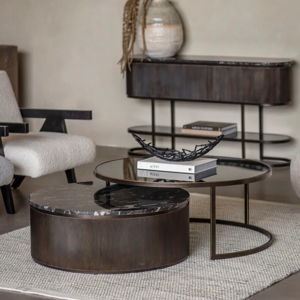 Black nesting coffee tables in a modern living room with a textured rug.