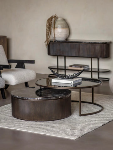 Black nesting coffee tables in a modern living room with a textured rug.