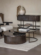 Black nesting coffee tables in a modern living room with a textured rug.