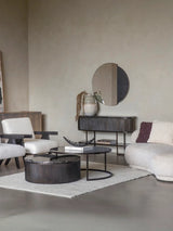 Black nesting coffee tables in modern living room with beige sofas and decor.