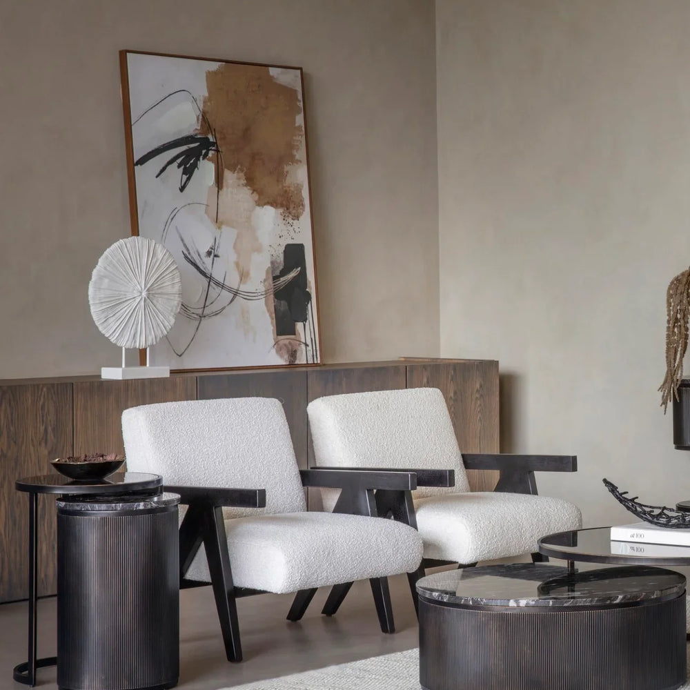 Black nesting tables in modern living room with white armchairs and abstract art.