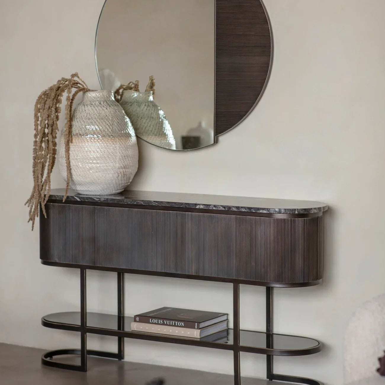 Black console table with decorative vases and books in a modern living room.