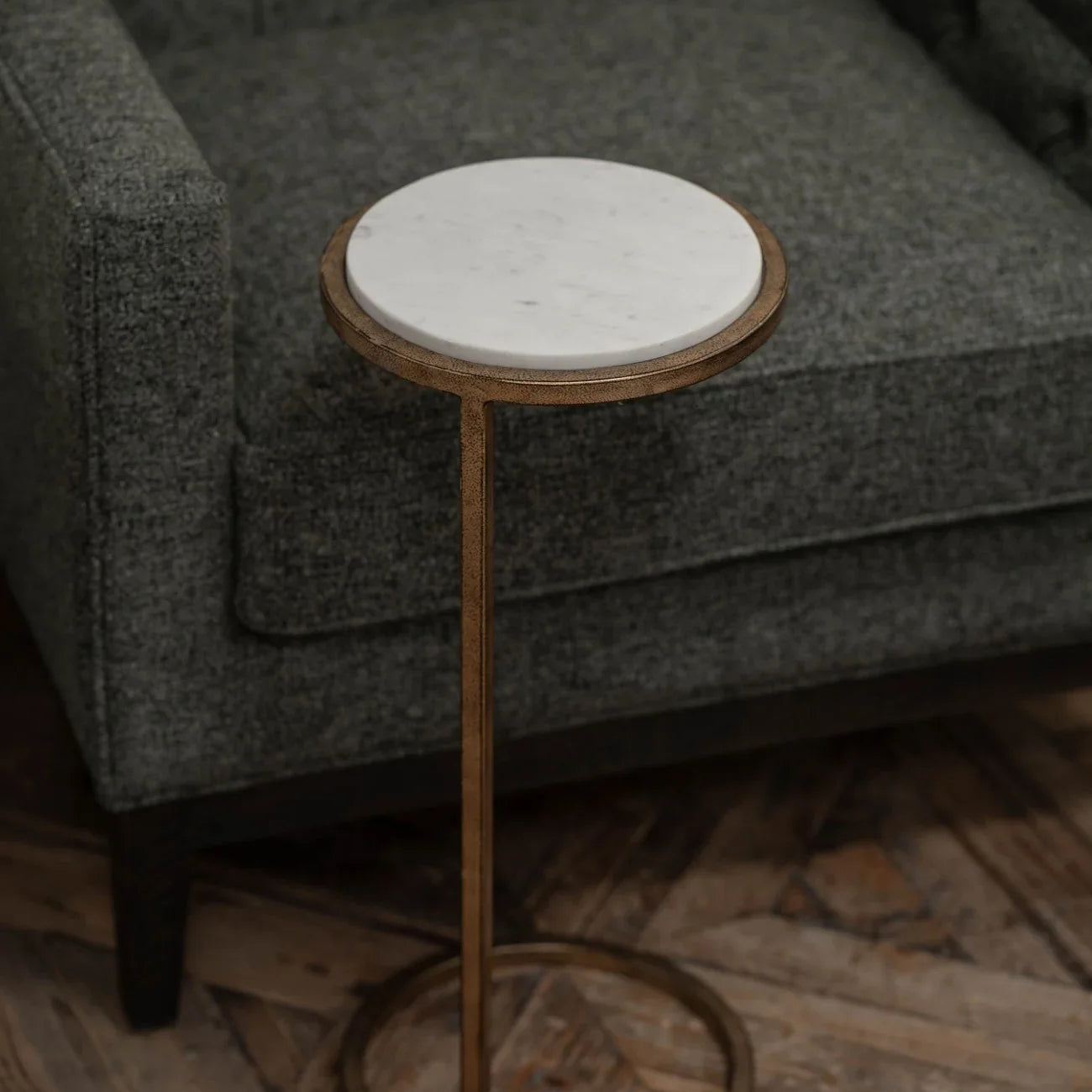 White marble-topped table beside a grey upholstered chair on wooden flooring.