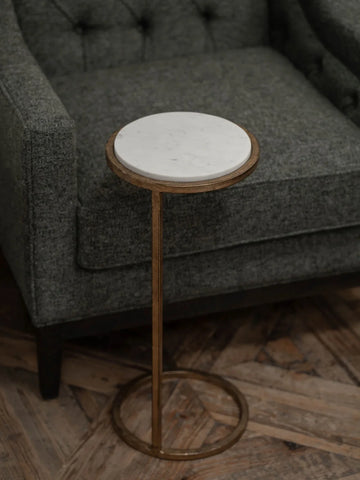 White marble-topped table beside a grey upholstered chair on wooden flooring.