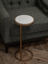 White marble-topped table beside a grey upholstered chair on wooden flooring.