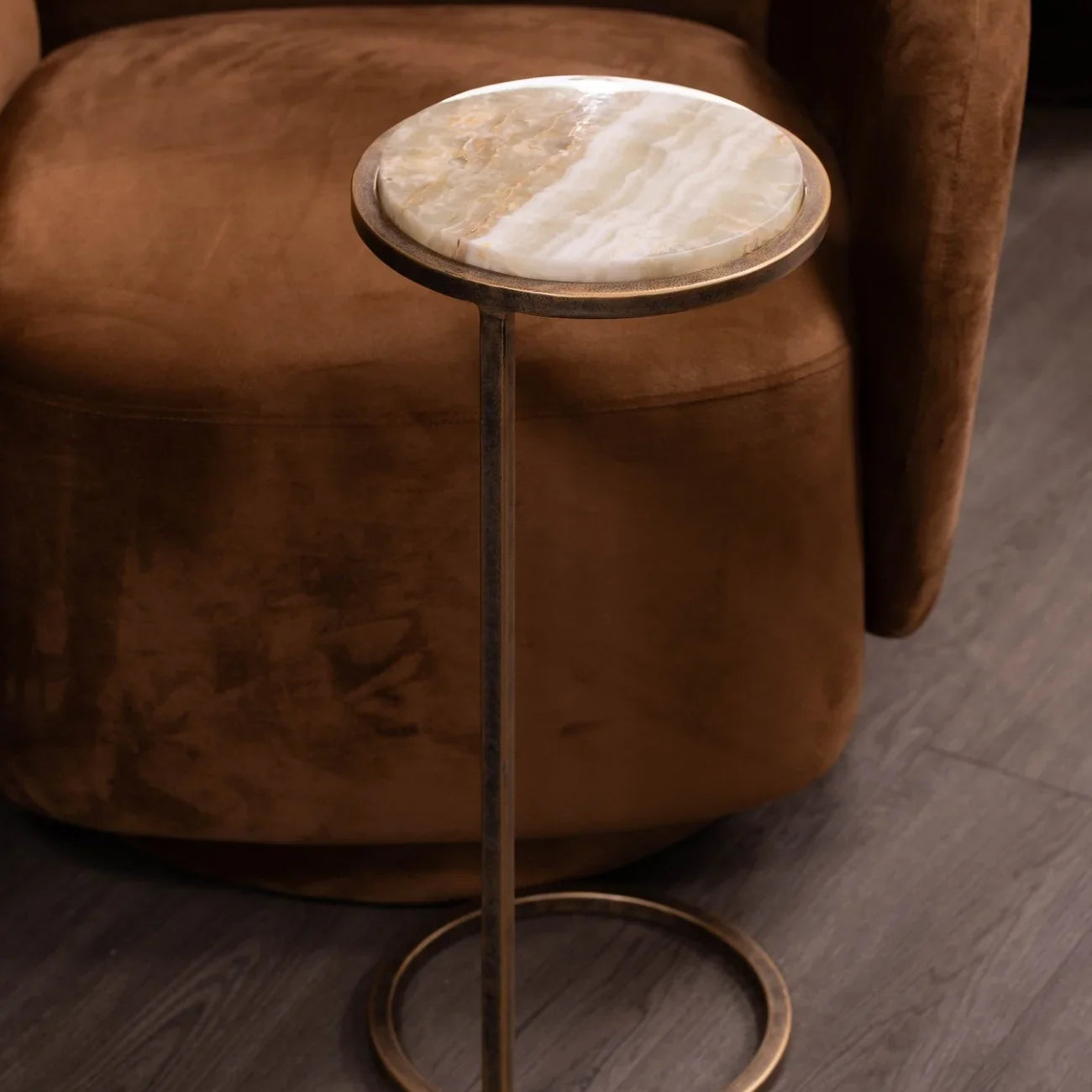 Round onyx-topped side table beside a plush brown chair.