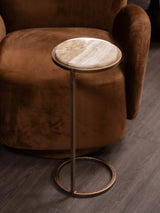 Round onyx-topped side table beside a plush brown chair.