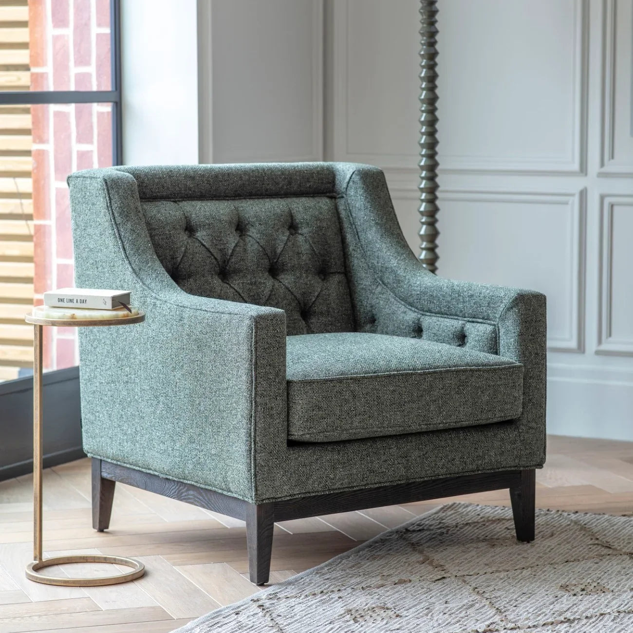 Green onyx side table next to a grey armchair in a modern living room setting.