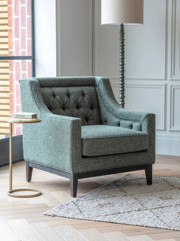 Green onyx side table next to a grey armchair in a modern living room setting.