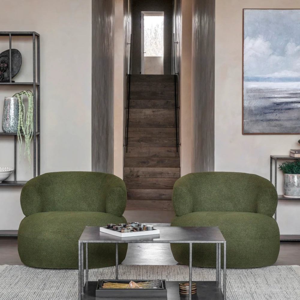 Mottled black coffee table in modern living room with green chairs and artwork.
