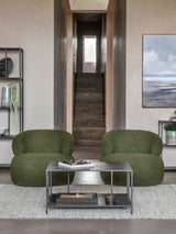 Mottled black coffee table in modern living room with green chairs and artwork.