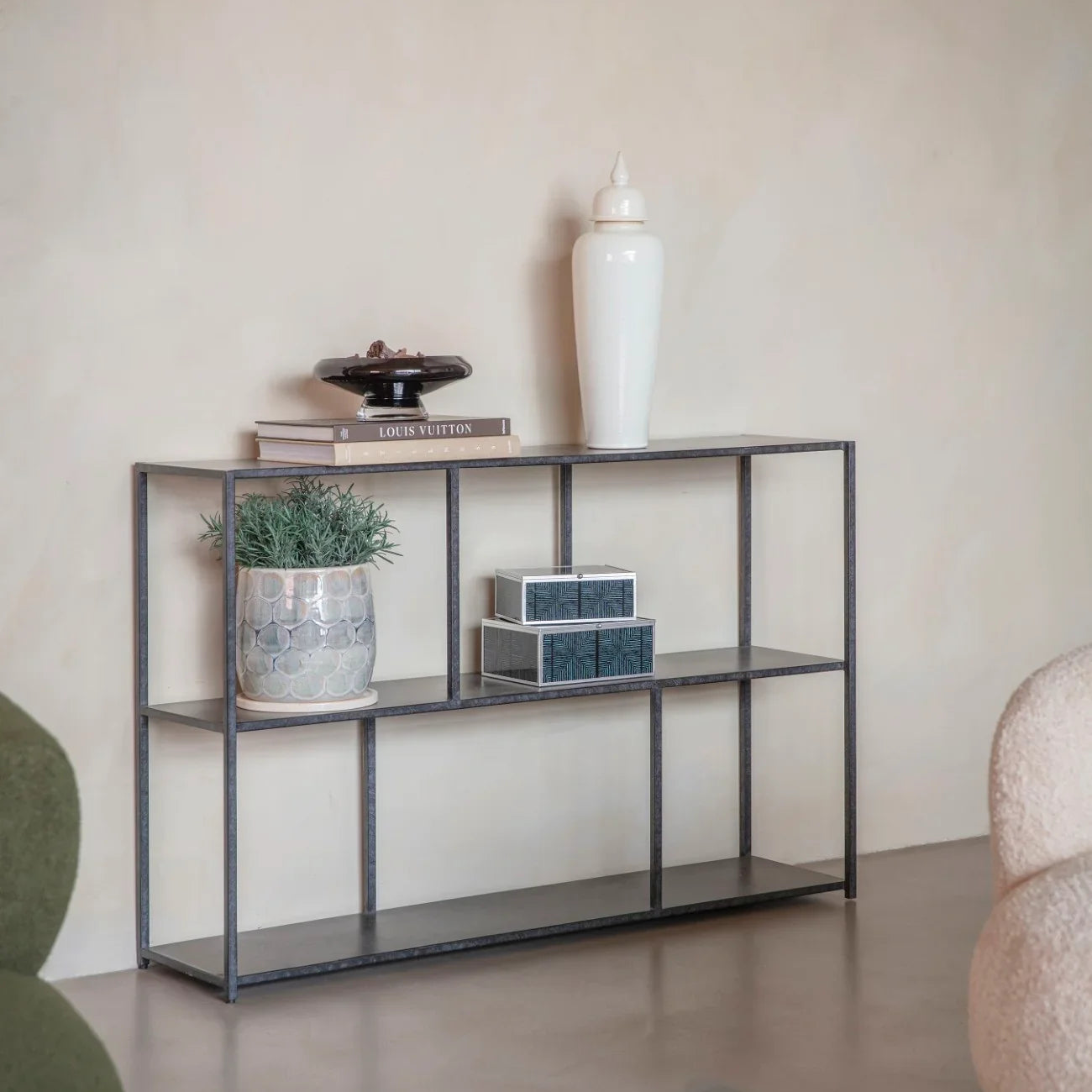 Mottled black console table with decor in a minimalist living room setting.