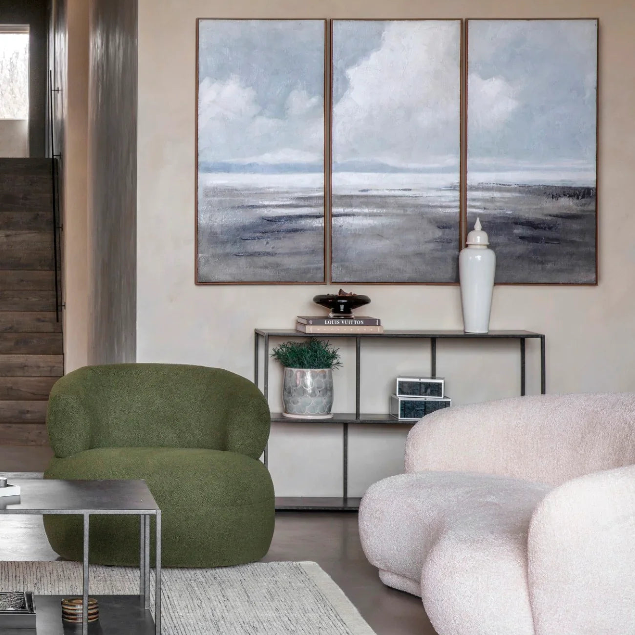 Console table in a modern living room with green and beige seating and abstract wall art.