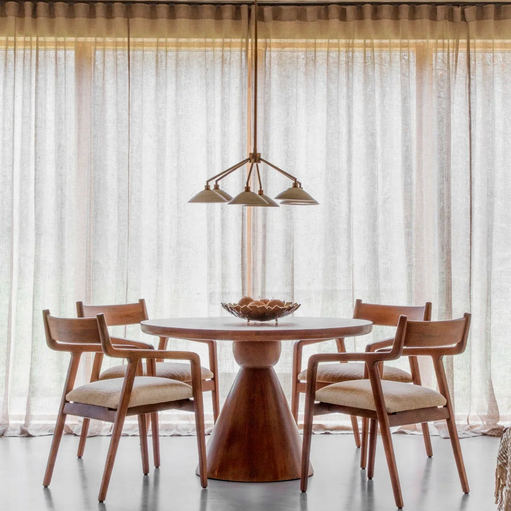 Round wooden table with chairs in a bright dining room setting.