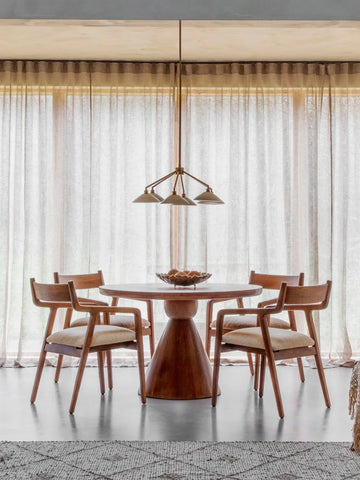 Round wooden table with chairs in a bright dining room setting.