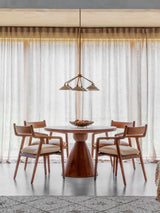 Round wooden table with chairs in a bright dining room setting.