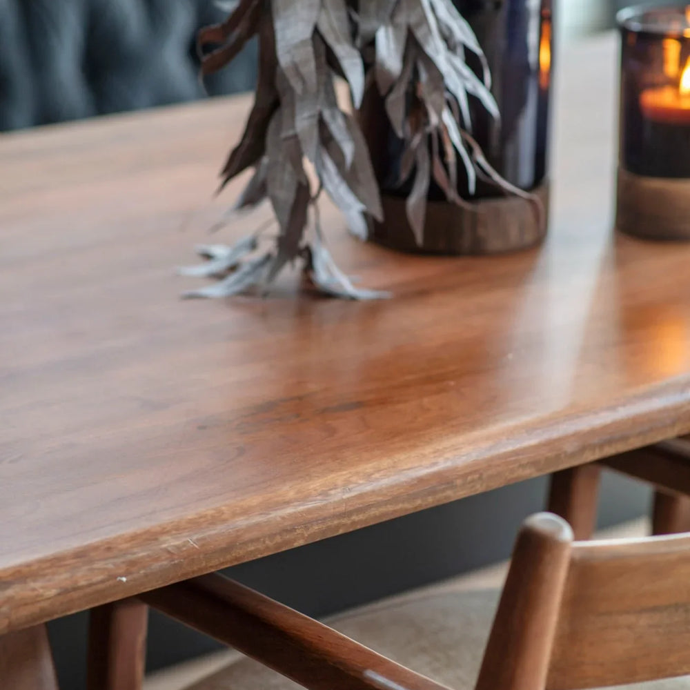 Wooden dining table with foliage and candles in a cozy setting.