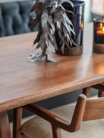 Wooden dining table with foliage and candles in a cozy setting.