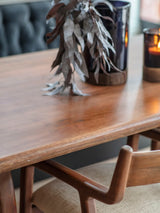 Wooden dining table with foliage and candles in a cozy setting.