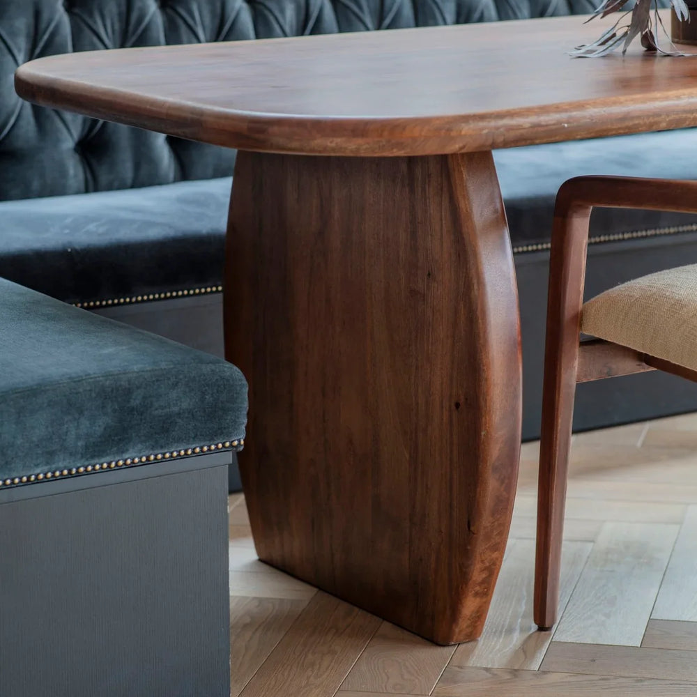 Smooth wooden dining table with curved edges in a cozy dining nook.