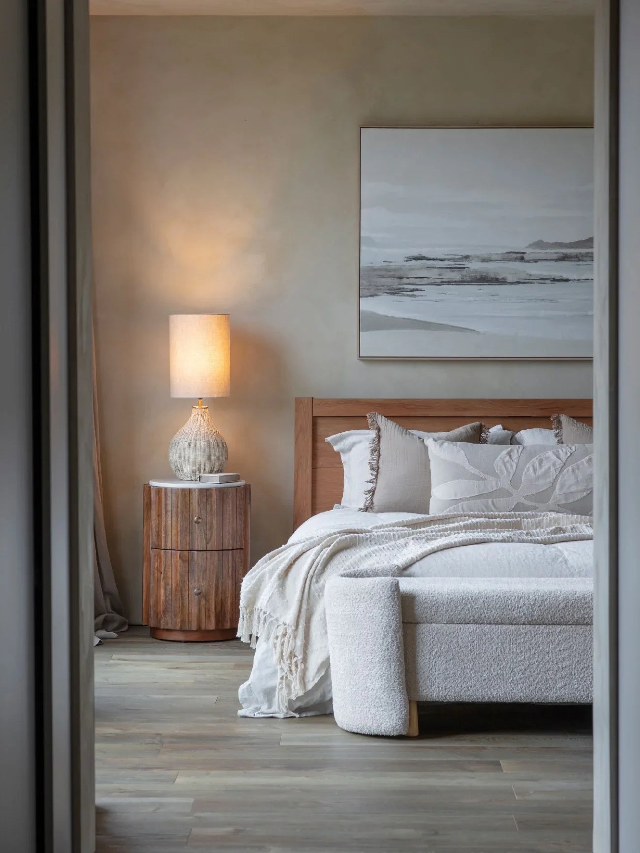 Curved wooden bedside with marble top in cozy bedroom setting.