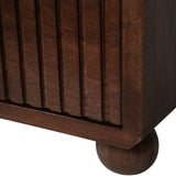 Dark wood chest corner with vertical grooves and rounded leg detail.