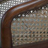 Dark wood armchair with intricate cane backrest detail.