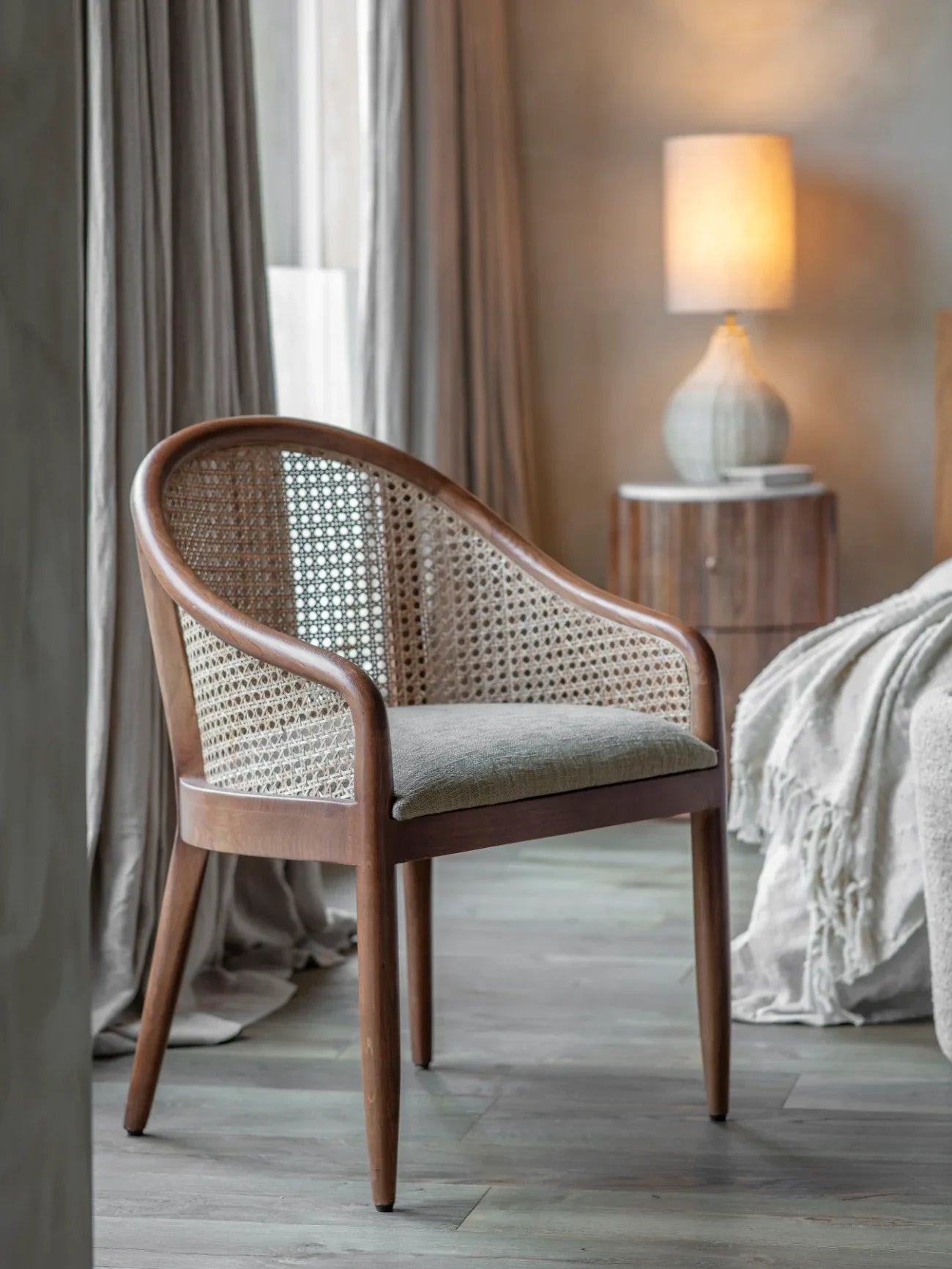 Oak armchair with cane back in cozy bedroom setting, soft lighting.