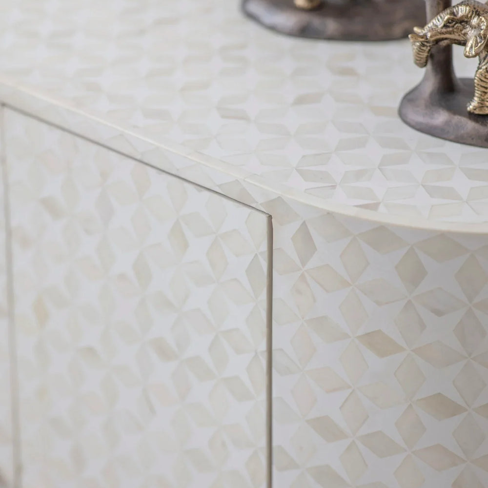 White geometric pattern on cabinet surface with decorative figurines.