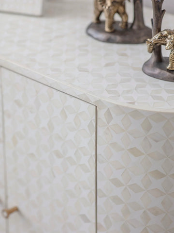 White geometric pattern on cabinet surface with decorative figurines.