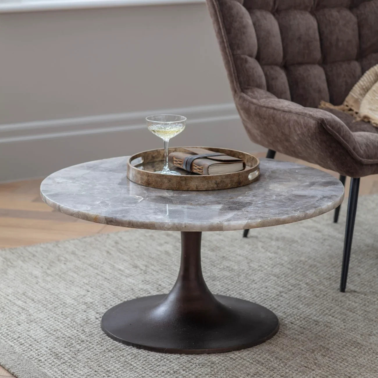 Round quartz coffee table with dark base in cozy living room setting.