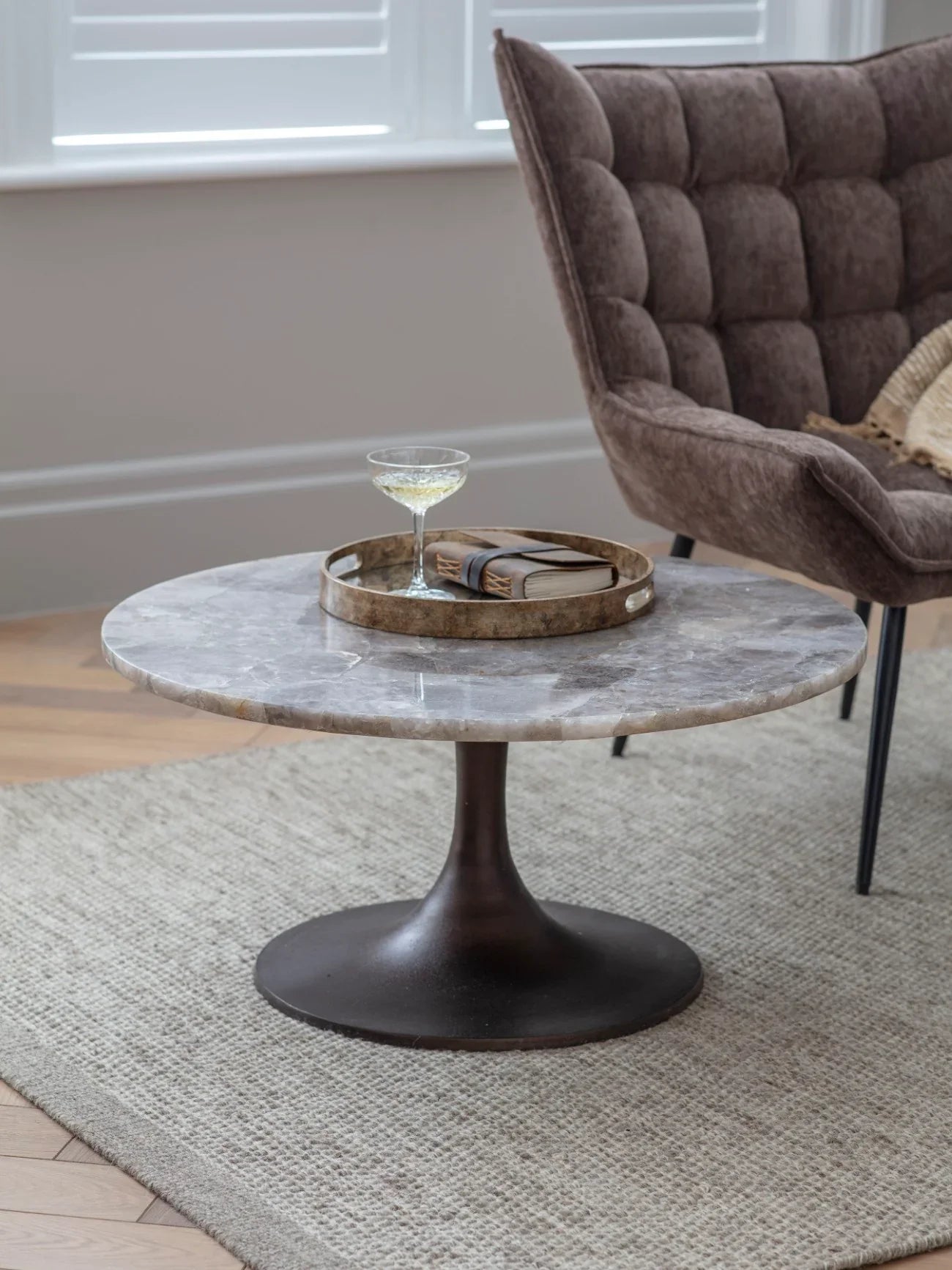 Round quartz coffee table with dark base in cozy living room setting.