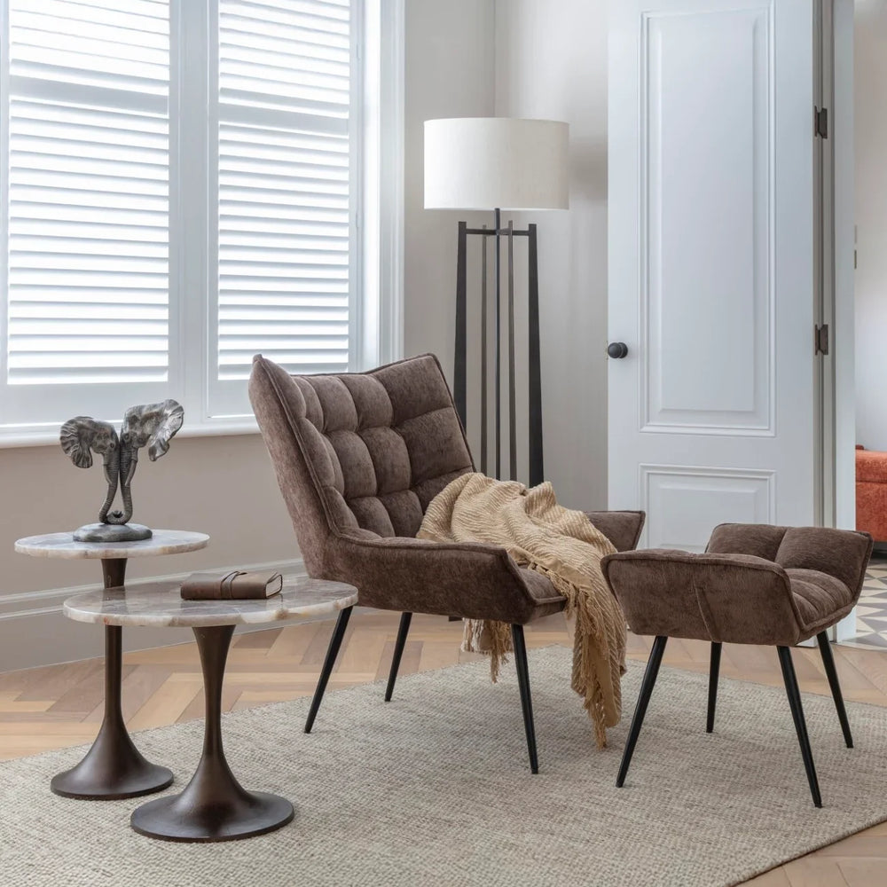 Two round stone-topped tables in a cozy living room with a brown armchair.