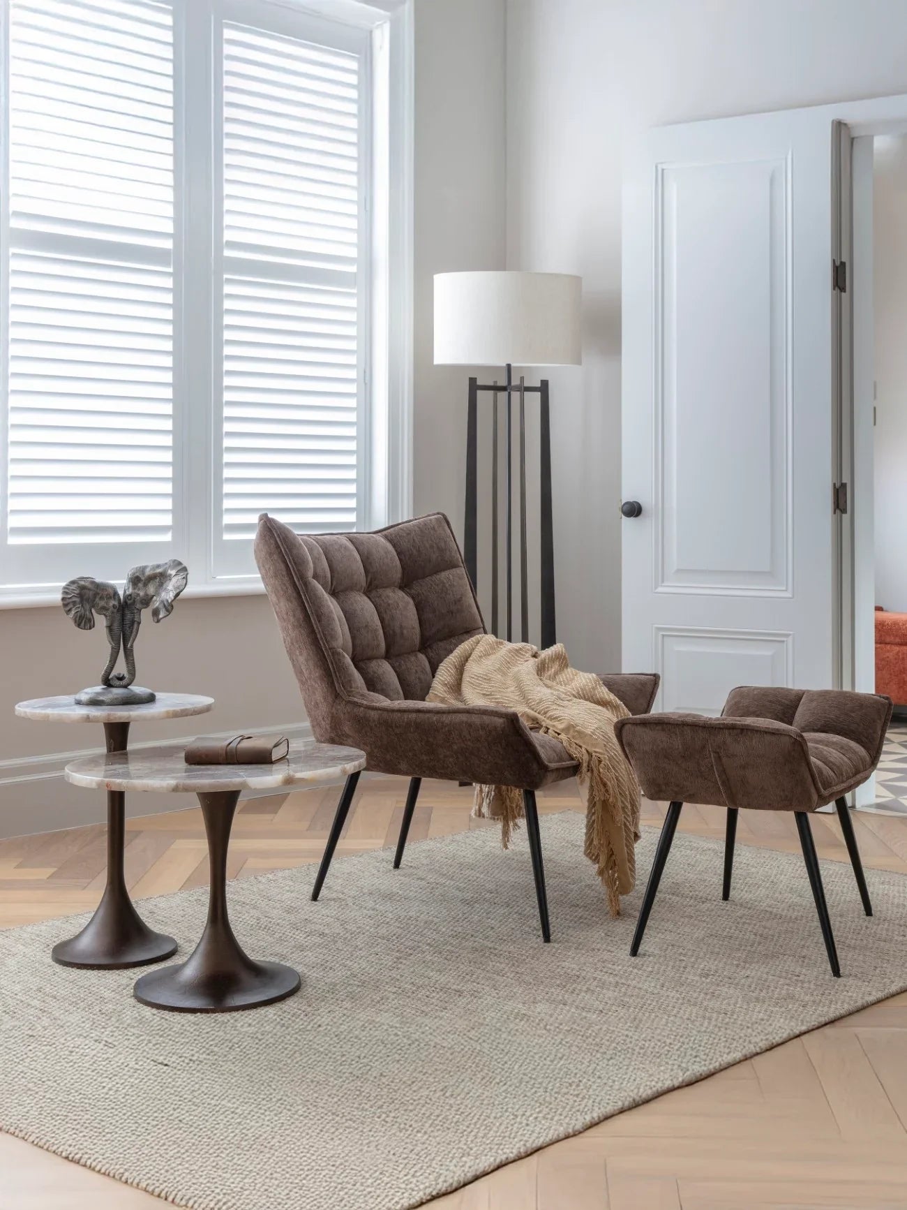 Two round stone-topped tables in a cozy living room with a brown armchair.