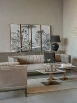 Marble side table in elegant living room with beige sofas and decorative panel art.