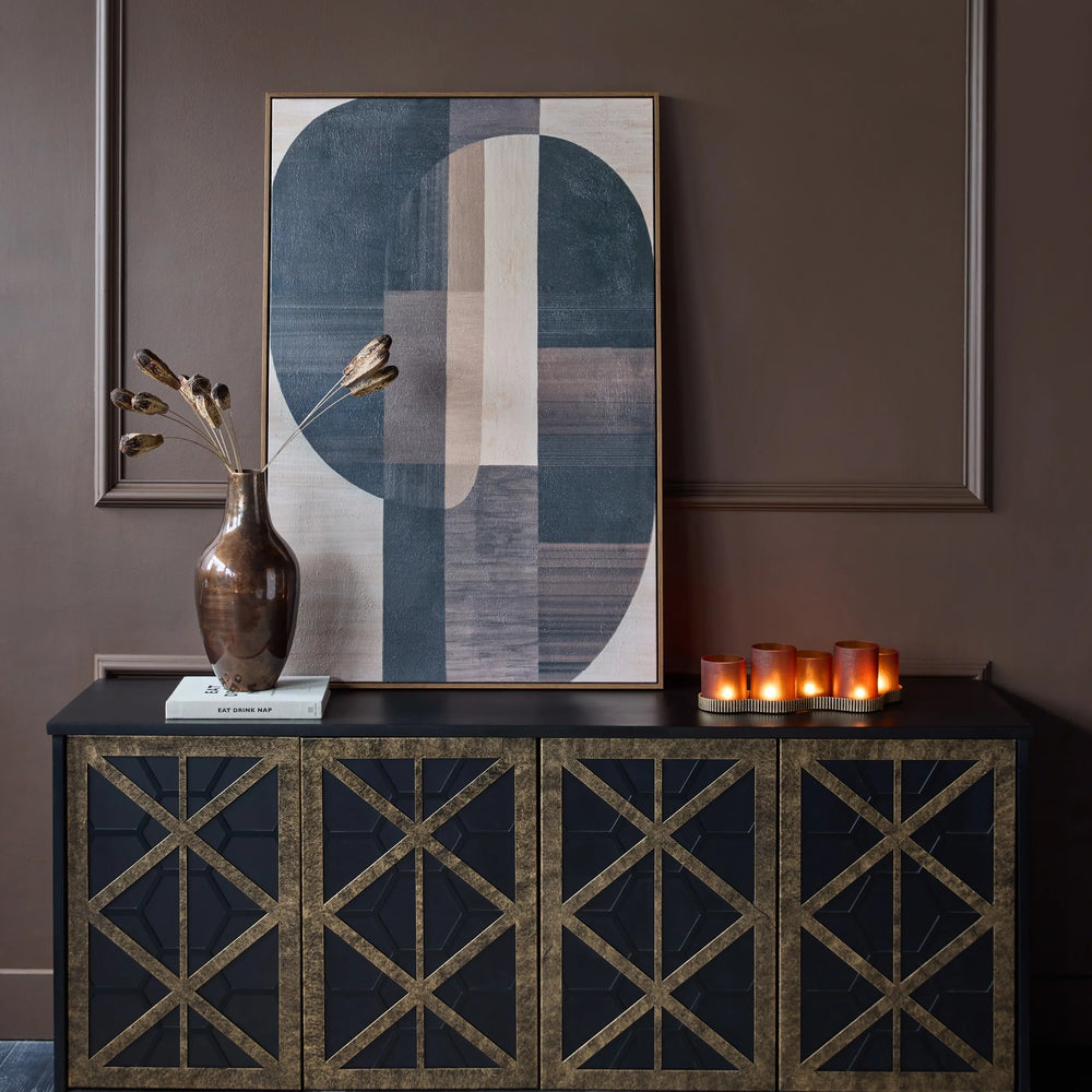 Black and gold sideboard in a brown room with abstract art and candles.