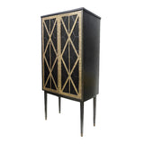 Black bar cabinet with gold fretwork design and tall slender legs.