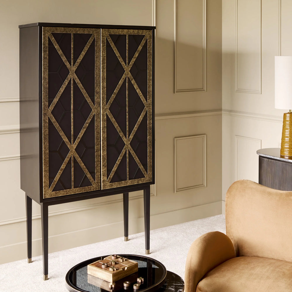 Black and gold bar cabinet in elegant living room with beige walls and plush armchair.